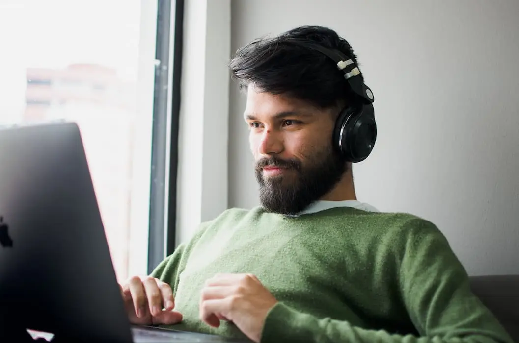 A man wearing headphones is using a laptop.