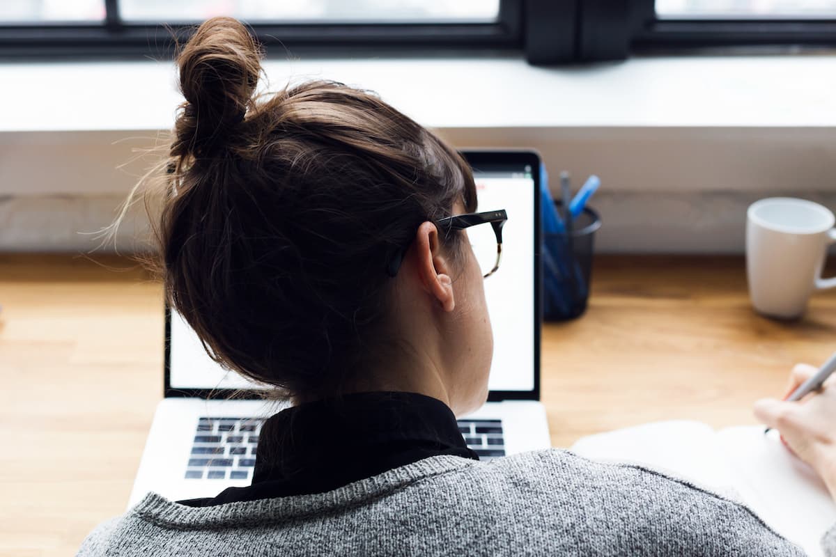 woman taking notes in fromt of a laptop